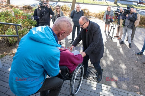 Głosowanie - Paweł Adamowicz wnosi kobietę na wózku do lokalu wyborczego
