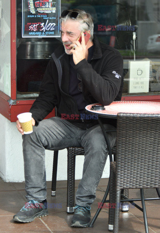 Chris Noth rozmawia przez telefon popijając kawę