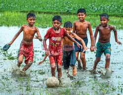 Chłopcy grają w piłkę na zalanych polach