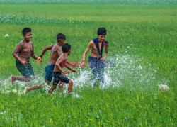 Chłopcy grają w piłkę na zalanych polach